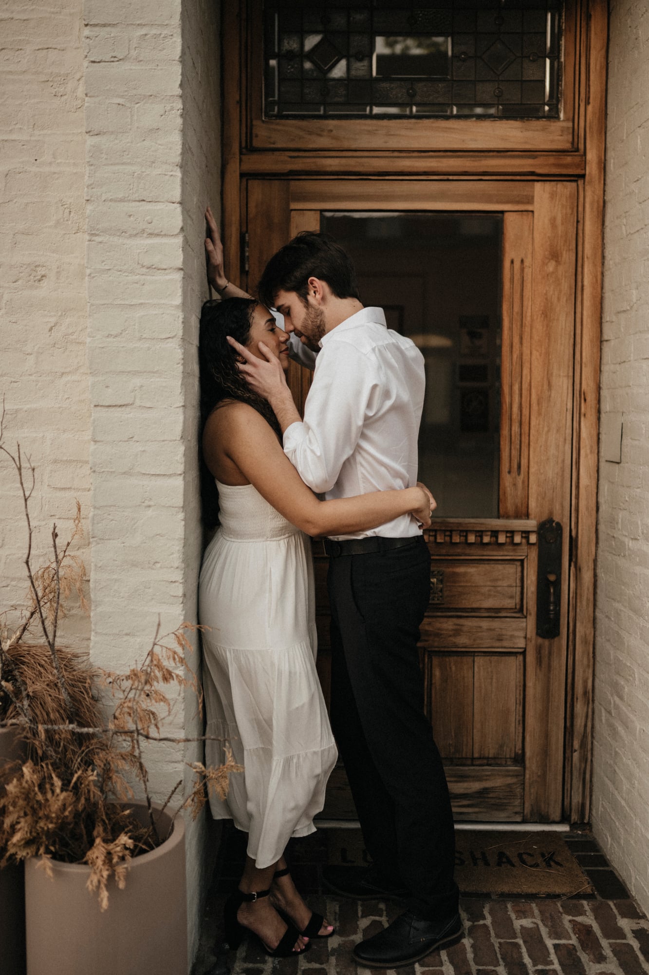 Couple sharing an intimate moment in a rustic brick entryway