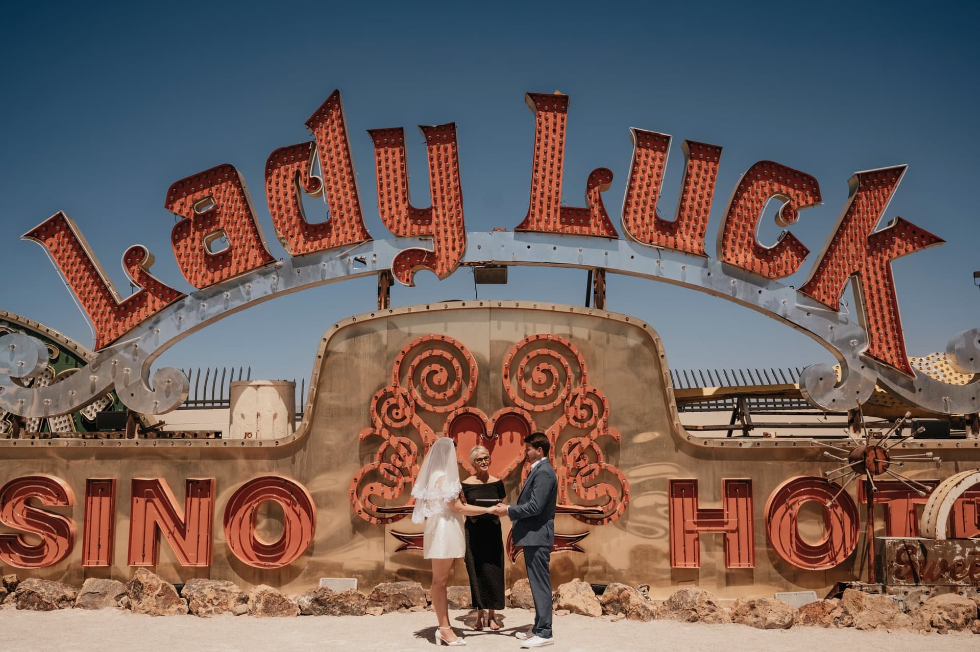 Bride and groom exchanging vows in front of the Lady Luck neon sign