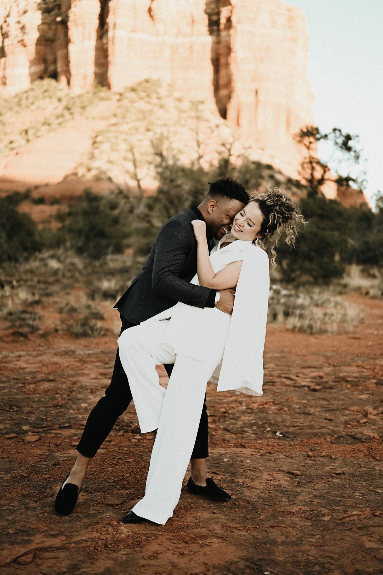 Couple holding hands among red rock formations in Sedona