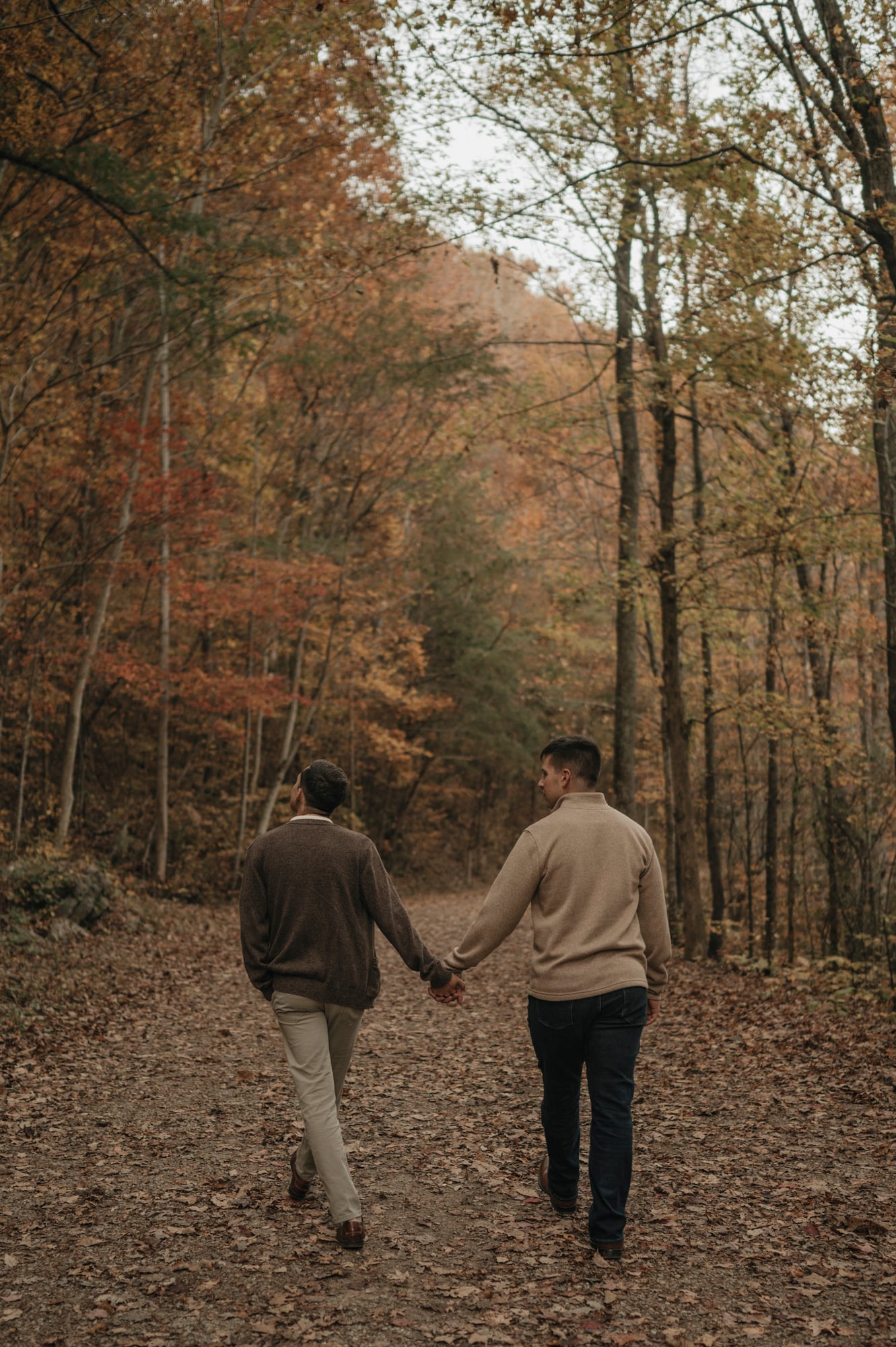 Couple walking away together down an autumn woodland trail