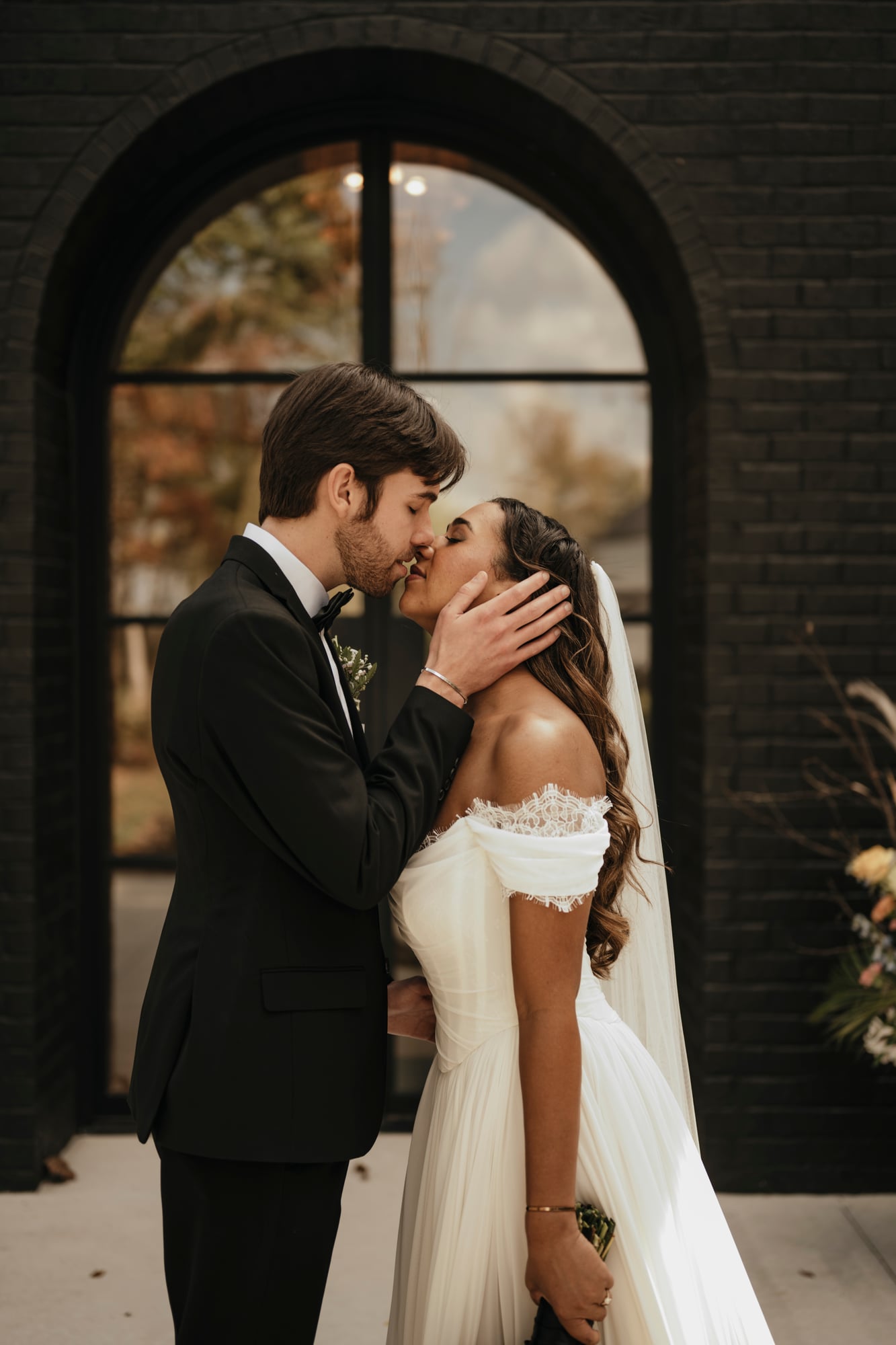 Bride and groom sharing a kiss in front of an arched window