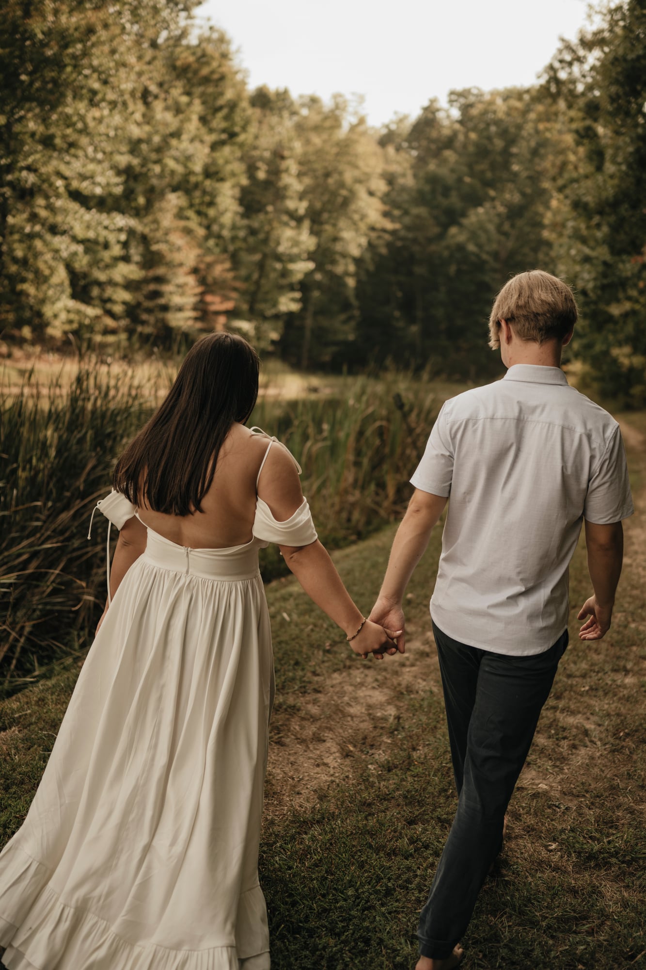 Couple walking away together on a path beside a pond