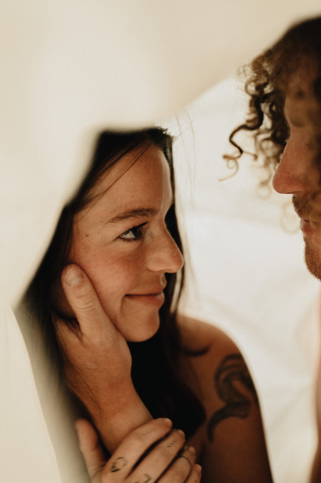 Intimate close-up of a couple holding hands under white linen